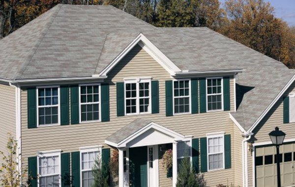Tan colored home with green shutters and white trim.